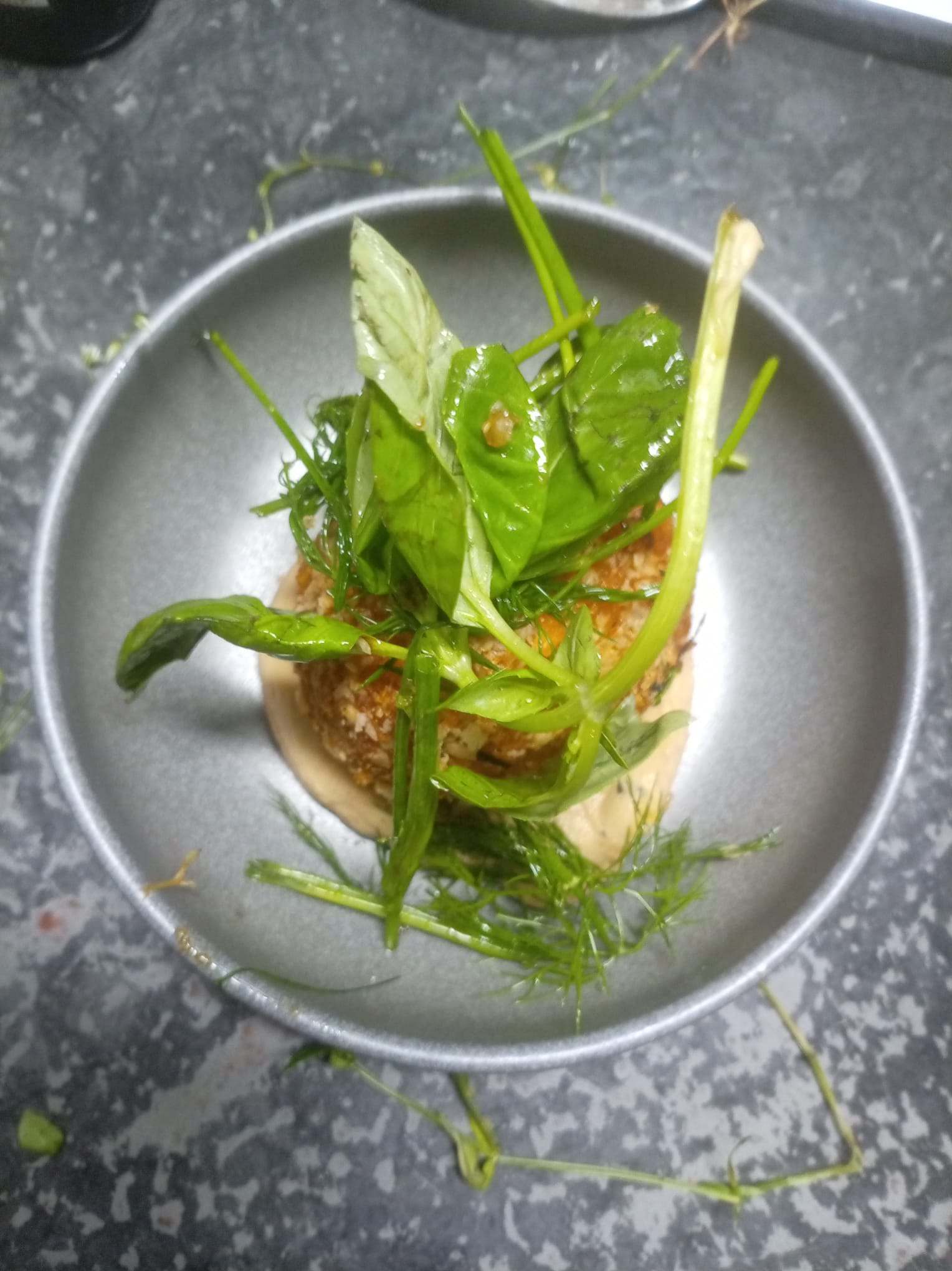 Assiette dressée en hauteur : jeunes pousses et herbes fraîches.